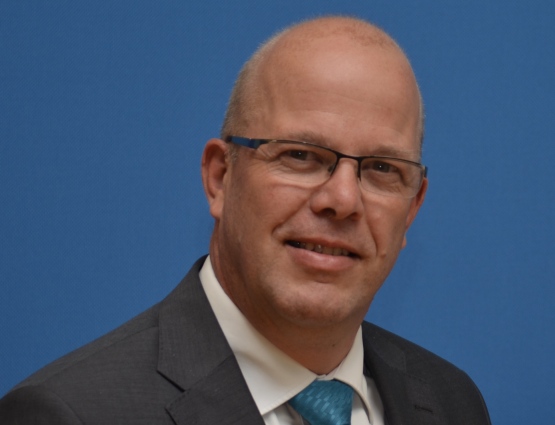 Rens Huizenga staat op de foto. Hij draagt een net pak en kijkt recht in de camera.