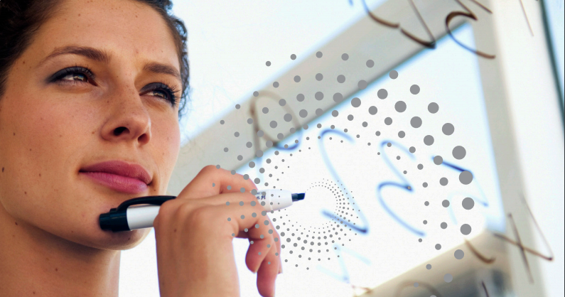 Een glazen whiteboard met daarachter een vrouw die een marker in haar hand houdt en aan het denken is. Op het whiteboard staan nummers.