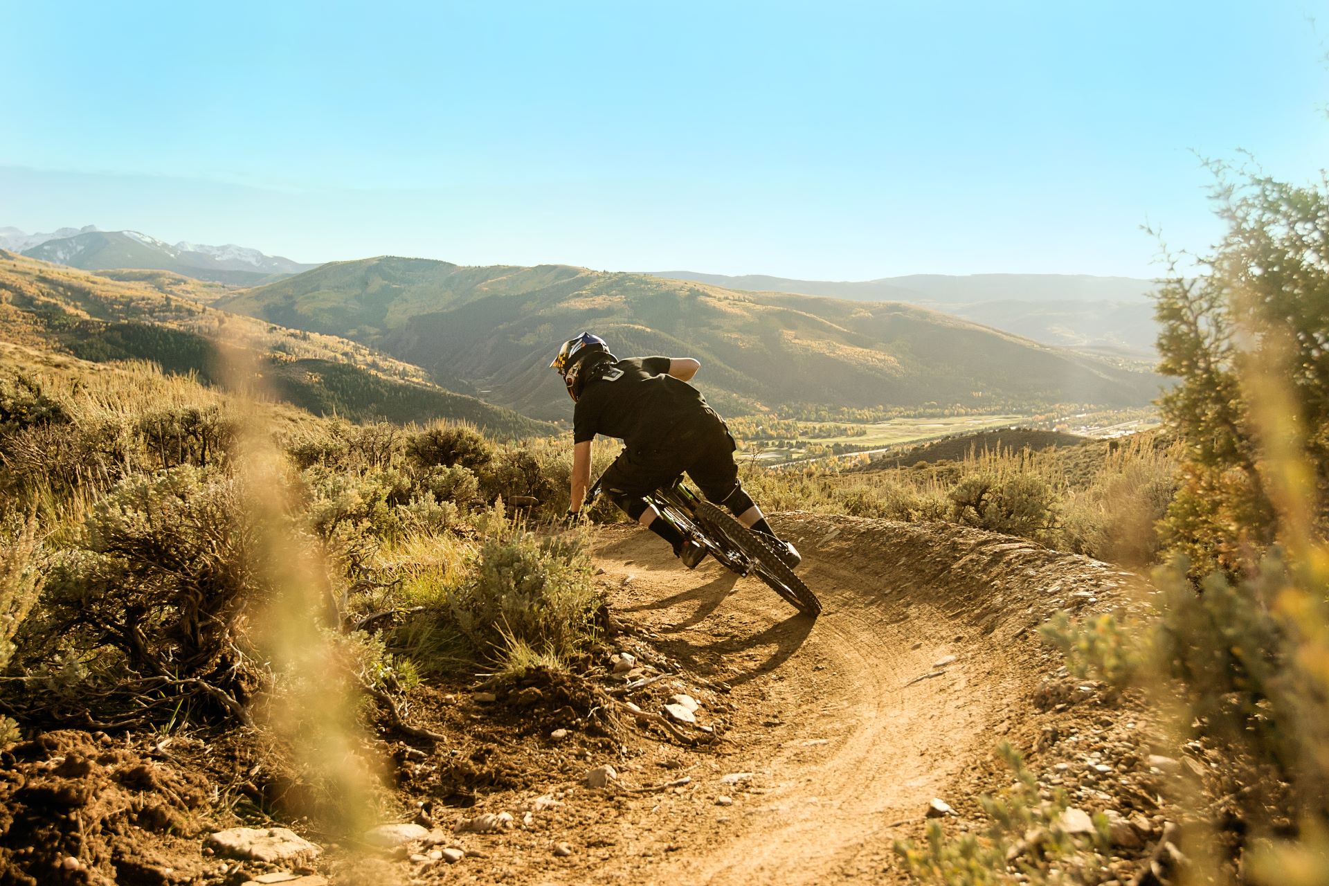 Een mountainbiker fietst over een ruig bergpad, omringd door adembenemende berglandschappen.