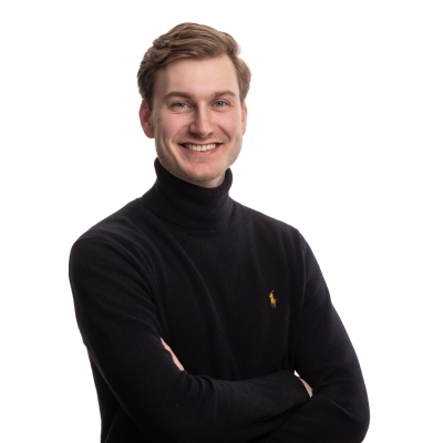 Portretfoto van Koen van den Belt, die vriendelijk glimlacht tegen een neutrale achtergrond.