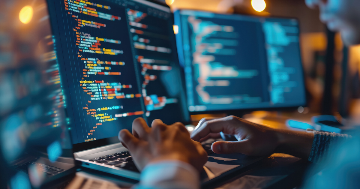 Een kleurrijke bannerafbeelding met de handen van een persoon die op een laptop aan het coderen is. De afbeelding benadrukt de focus op technologie en softwareontwikkeling.