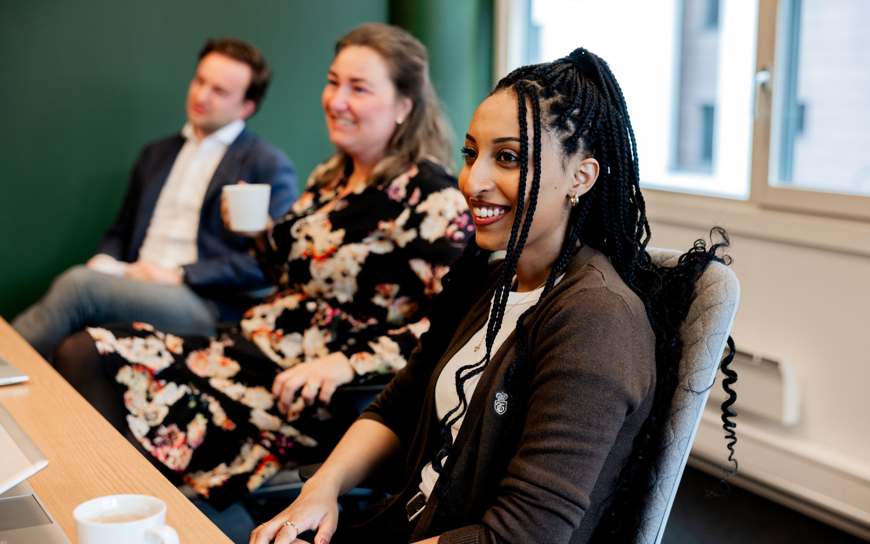 Three people sitting around a meeting and smiling