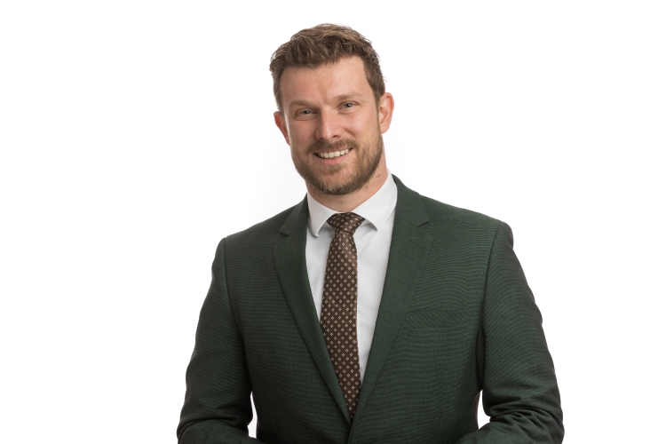 A man wearing a green suit and tie stands confidently, showcasing a stylish and professional appearance.