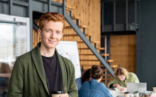 young man in the office is looking straight to the camera