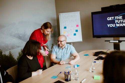 a group of people in the conference room discussing about colorful sticky notes