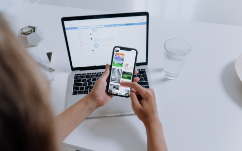 woman holding cellphone in front of laptop and showing charts