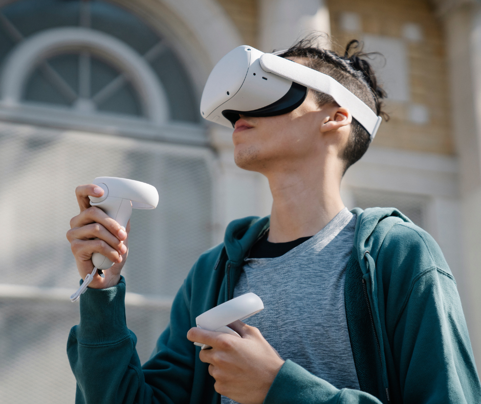 młody mężczyzna z założonymi okluarami VR i dwoma padami w kazdej ręce