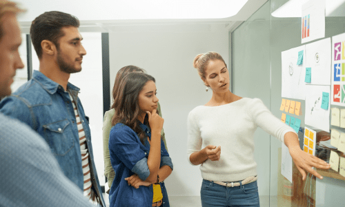 a group of people in the conference room is pointing on colorful sticky notes