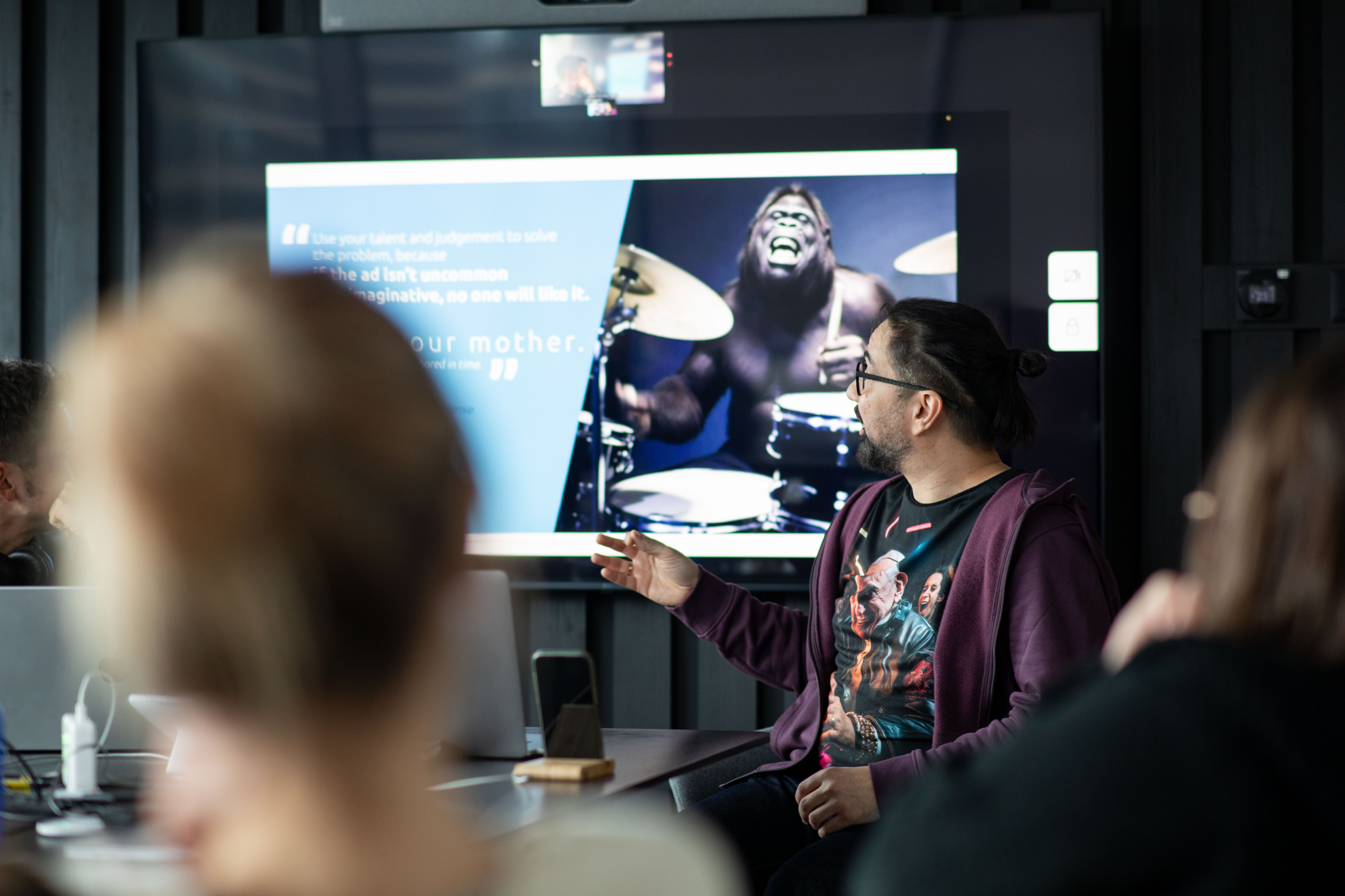 młody mężczyzna w okularach przedstawia na telewizorze w sali konferencyjnej prezentację technologiczną