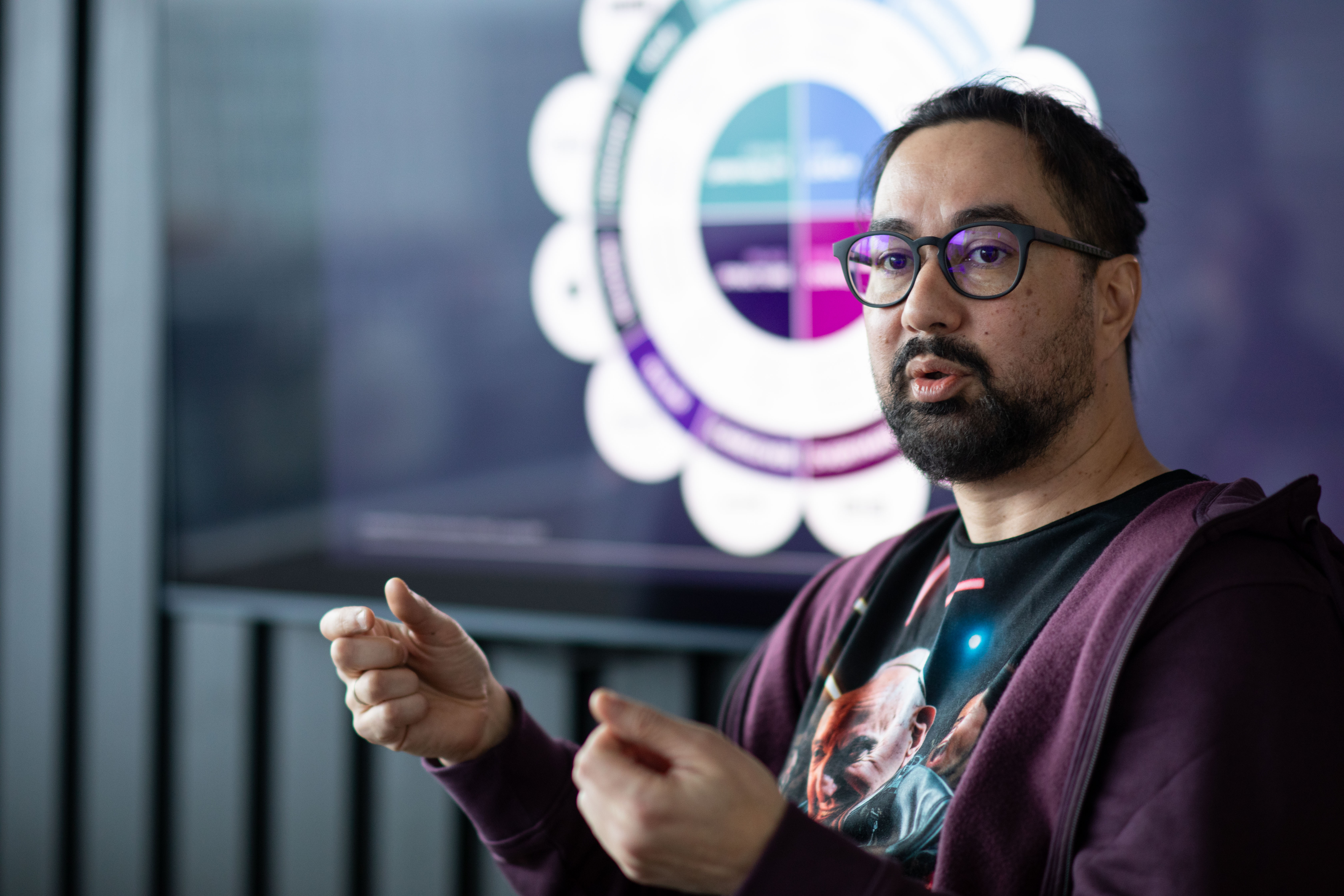 a man in glasses is presenting someting on the screen in the conference room