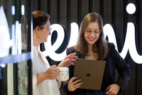 dwie kobiety, jedna trzymająca tablet i słuchająca drugiej