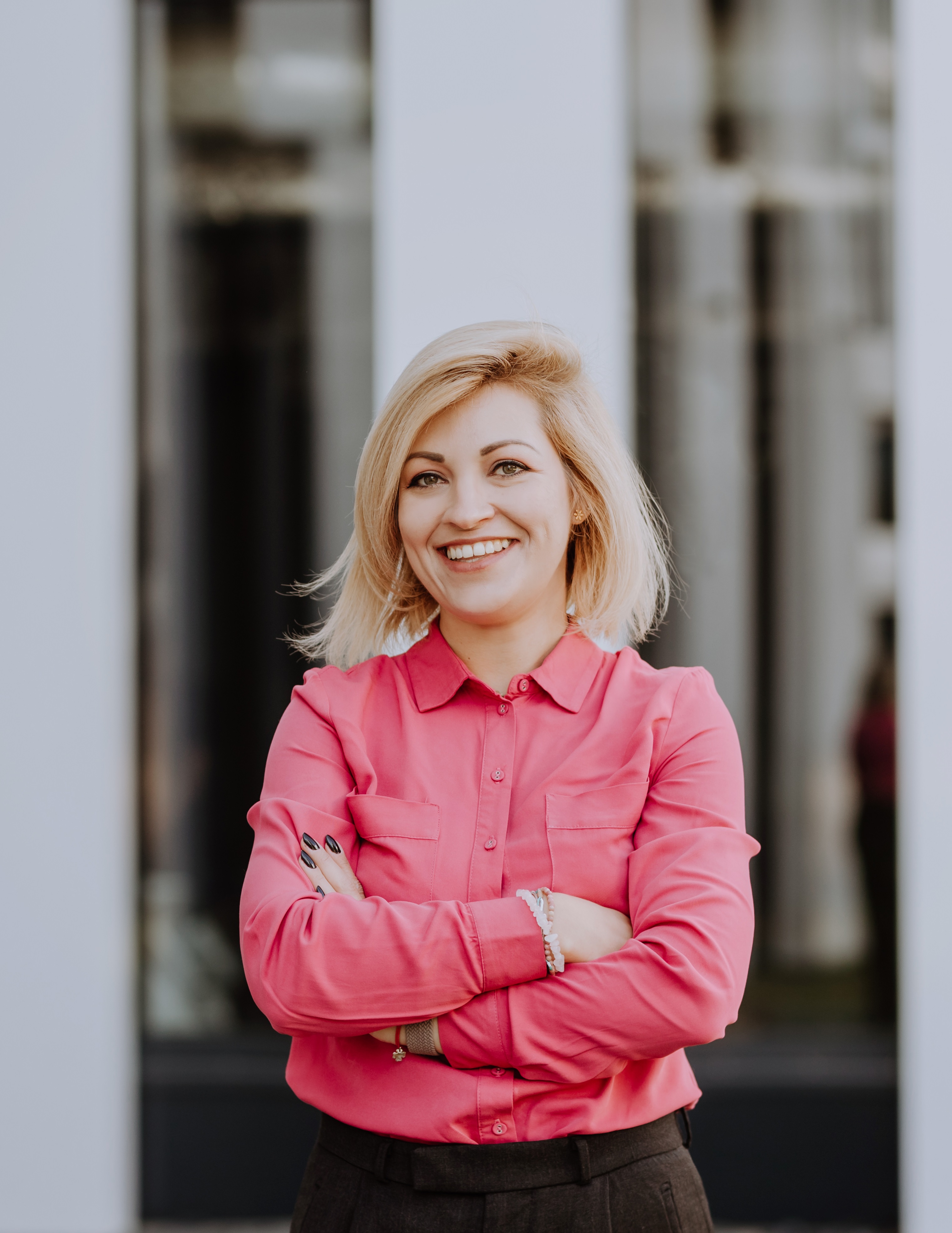 young woman stands outside the office in a pink shirt