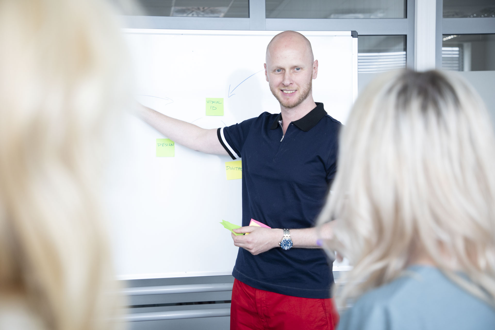 a young bold man is leading the meeting in front of a group of people