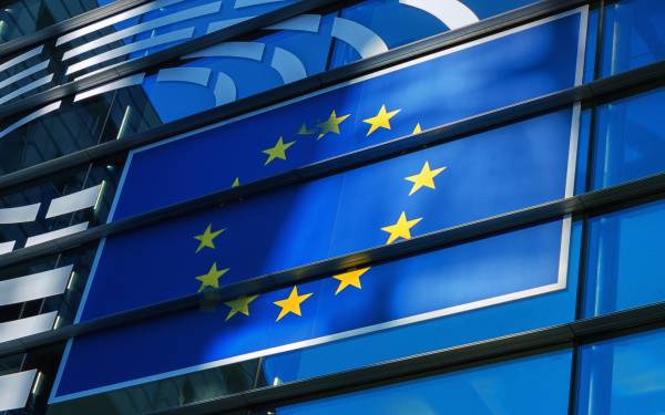 European Union flag displayed on a building with glass panels and metal beams in the background.